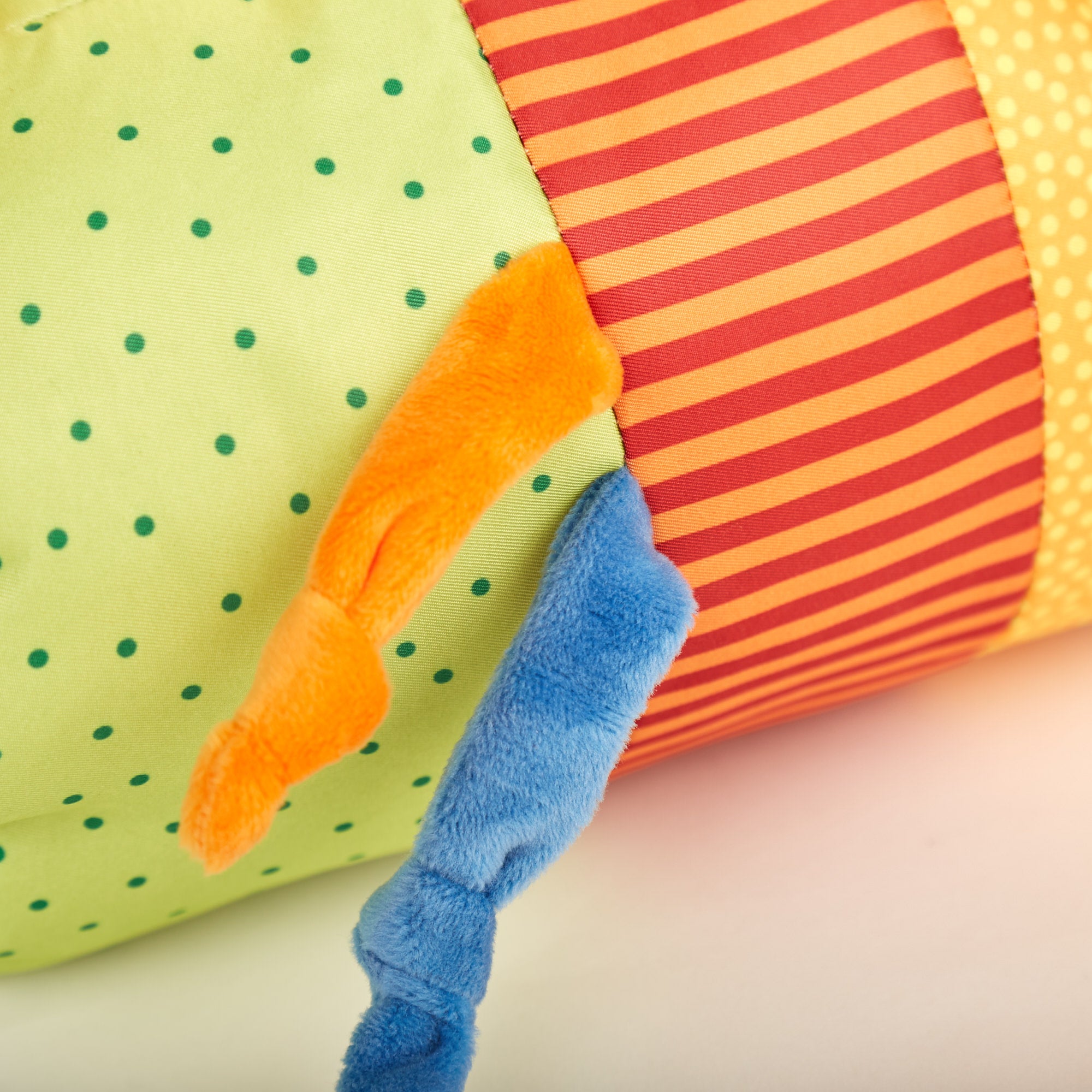 Poduszka Rolka 30cm, wałek sensoryczny do nauki raczkowania, z kolorowymi tkaninami w zielone kropki i pasy, oraz miękkimi, pluszowymi elementami stymulującymi zmysły i rozwój motoryczny maluszka.