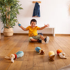 Uśmiechnięty chłopiec bawi się Zestawem miękkich Kręgli dla dzieci. Pluszowe kręgle-zwierzątka i piłeczka rozwijają motorykę i zmysły w formie radosnej gry.