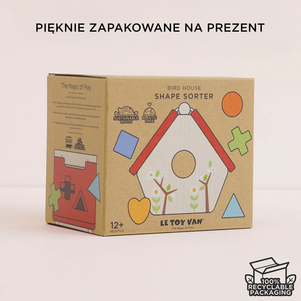 Eleganckie, ekologiczne opakowanie drewnianego sortera kształtów domek dla ptaków Le Toy Van, idealne na prezent. Brązowe kartonowe pudełko z barwną grafiką domku i informacjami o zrównoważonym drewnie, braku plastiku oraz 100% recyklingu. Wskazuje wiek 12+ miesięcy.
