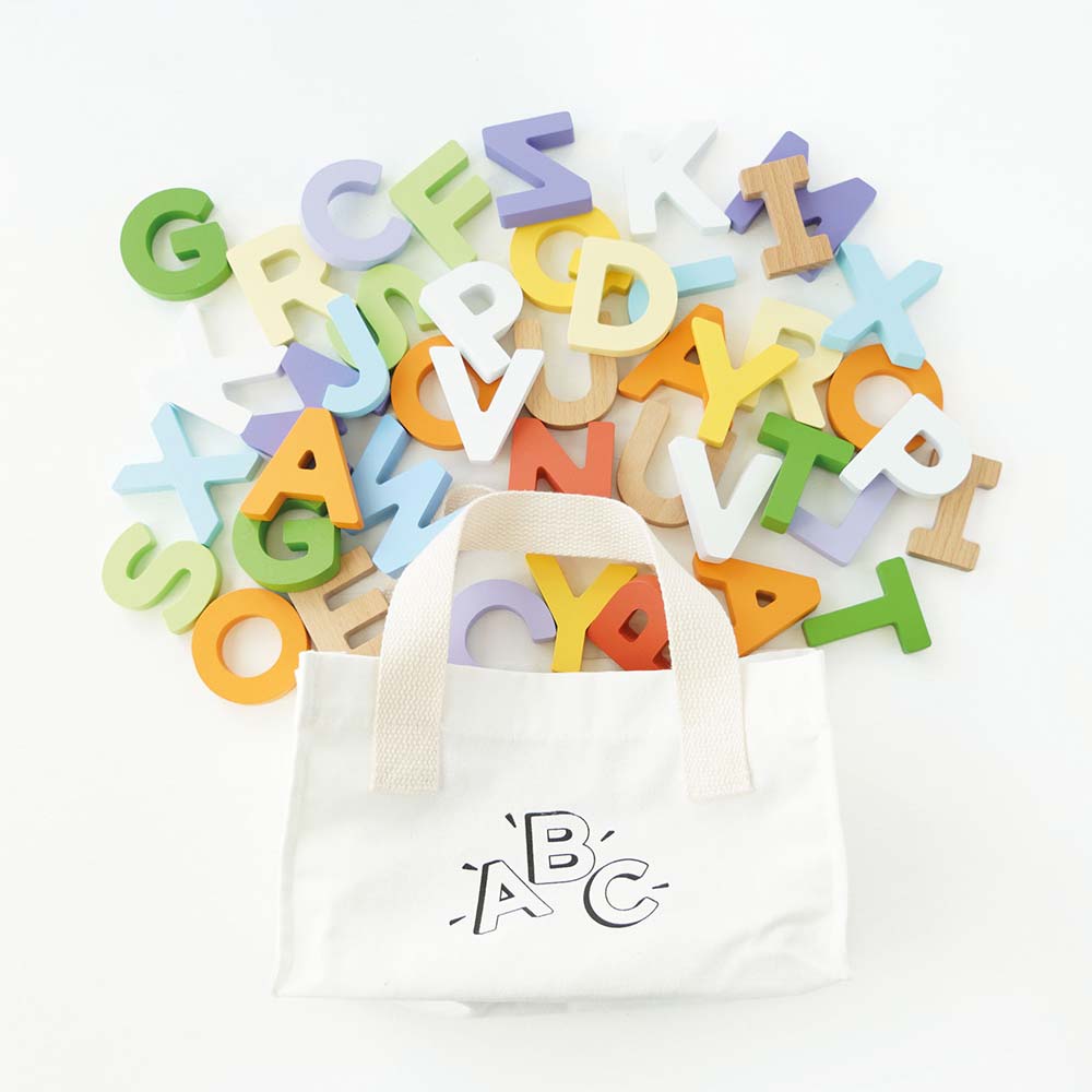 Kolorowy zestaw 60 drewnianych literek tęczowych, wysypujących się z przenośnej torby z logo ABC. Idealna zabawka edukacyjna do nauki alfabetu, czytania i pisania dla dzieci.