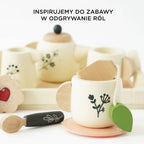 Uroczy drewniany zestaw do herbaty dla dzieci w brytyjskim stylu: filiżanka z torebką herbaty, imbryk i łyżeczka, zdobione motywami roślinnymi, idealne do zabawy w odgrywanie ról.