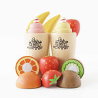 Drewniany zestaw Fruit & Smooth: dwa kubki ze smoothie, banany i pokrojone owoce – truskawka, kiwi, pomarańcza. Idealny do zabawy w zdrową kuchnię.