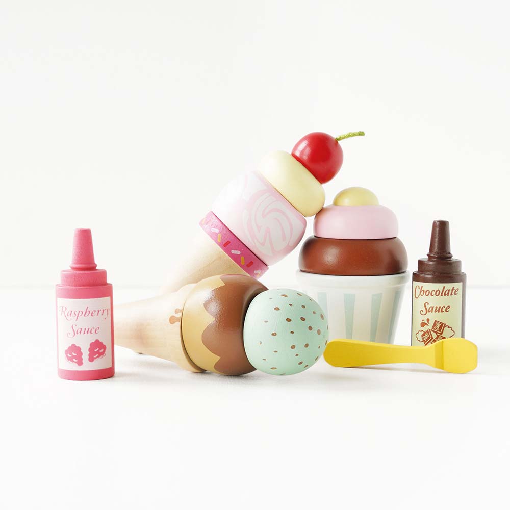 Drewniane lody rożki Carlo's Gelato: apetyczny zestaw zabawkowych lodów w pastelowych kolorach, z sosami malinowym i czekoladowym oraz łyżeczką, idealny do kreatywnej zabawy w lodziarnię dla dzieci.