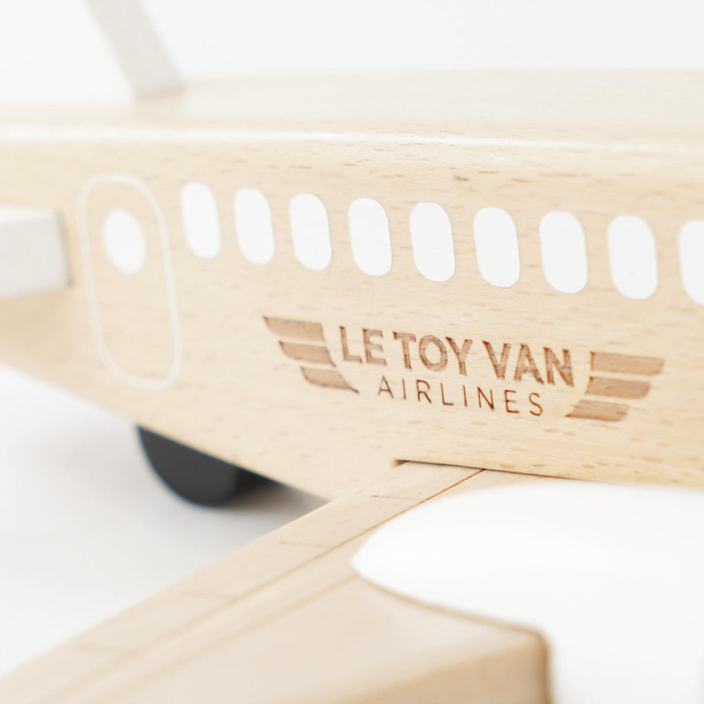 Drewniany samolot Le Toy Van Airlines z grawerowanym logo i białymi akcentami, ukazujący naturalną strukturę drewna.