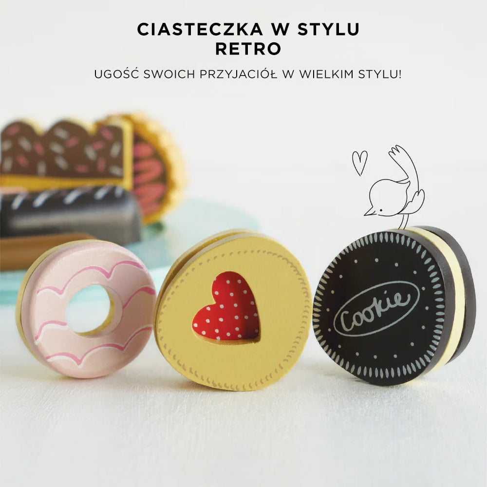 Trzy urocze, bogato zdobione drewniane ciasteczka zabawki: różowy pączek, żółte ciastko serce z czerwoną wstawką oraz ciemne ciastko typu sandwich z napisem 'Cookie'. Wykonane z bezpiecznego drewna i pastelowych, nietoksycznych farb.
