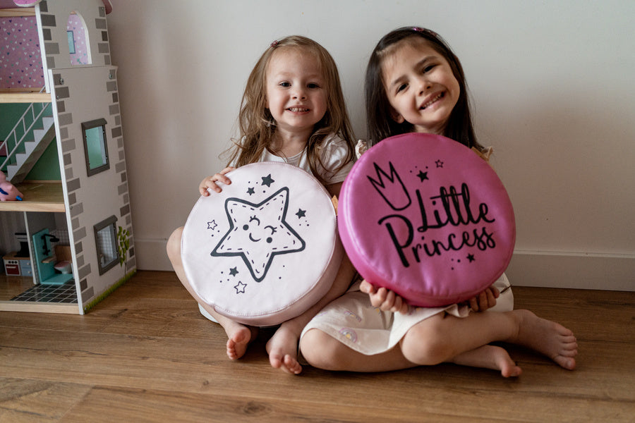 Uśmiechnięte dziewczynki prezentują poduszki ekoskóra LITTLE PRINCESS: jasnoróżową z wesołą GWIAZDKĄ i fuksjową z napisem LITTLE PRINCESS oraz koroną. Idealna dekoracja do pokoju dziewczynki, dodająca bajkowego uroku.