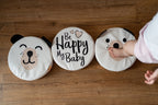 Trzy białe poduszki z ekoskóry dla dzieci na podłodze: PIESEK z uszkami, Be Happy My Baby i zwierzęcy wzór, z nóżką dziecka. Idealne do kącika zabaw w pokoju dziecięcym.