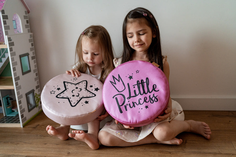Różowe poduszki ekoskóra dla dzieci z nadrukami Little Princess i gwiazda. Dwie dziewczynki bawią się okrągłymi, wygodnymi poduszkami o grubości 6 cm, idealnymi do pokoju dziecięcego lub jako prezent.
