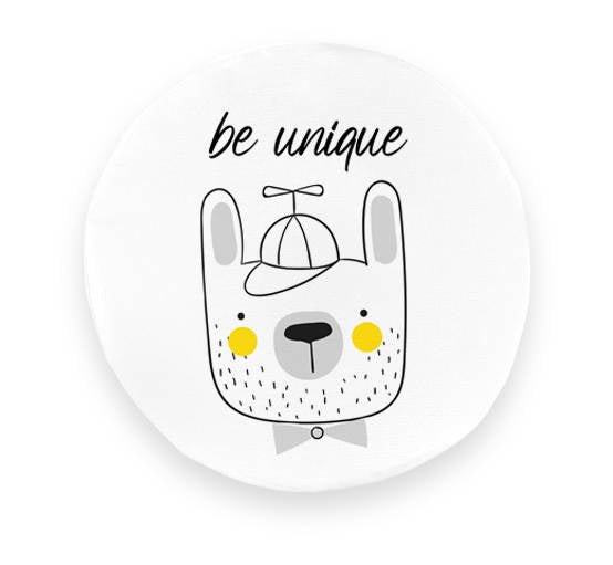 Okrągła poduszka z ekoskóry dla dzieci, biała, z motywem uroczego misia w czapce i inspirującym napisem „be unique”. Ożywia pokój dziecięcy.