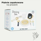 Elegancki drewniany zestaw obiadowy Le Toy Van dla dzieci 2+, zawierający talerze, sztućce, kubek i filiżankę, w kolorach drewna, błękitu i bieli z motywami roślinnymi. Estetycznie zapakowane akcesoria kuchenne idealne na prezent.